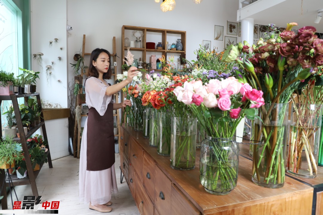 王黎媛是一名河南姑娘，在昆明念完大學(xué)后，就再也舍不下春城的藍天陽光、青山碧水，更舍不下這里的四時繁花，于是就干脆留了下來，成了一名媒體人。2017年的時候又毅然辭去工作，創(chuàng)業(yè)開起了花店，成了都市里的一名“花房姑娘”。圖為王黎媛在自己的花店中整理鮮花。新華網(wǎng) 周亞平/攝 念新洪/文